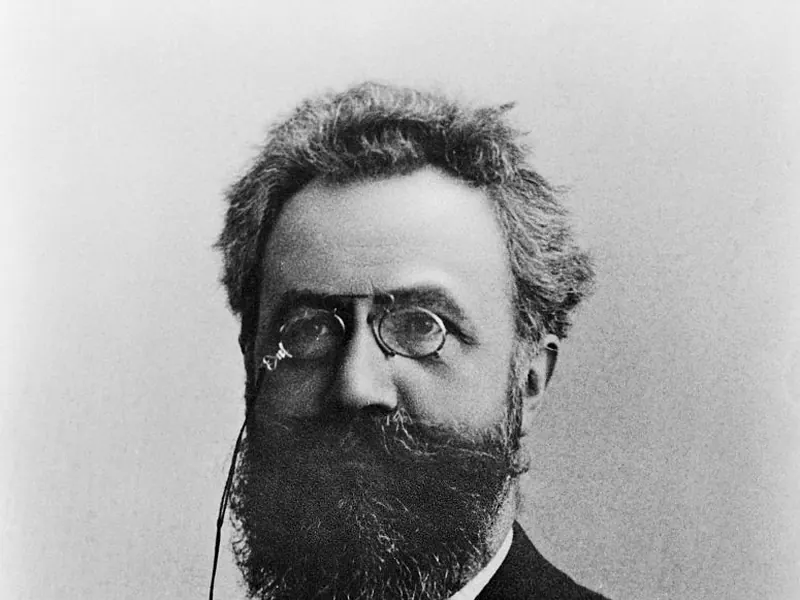 An old black-and-white portrait of a bearded man in a suit