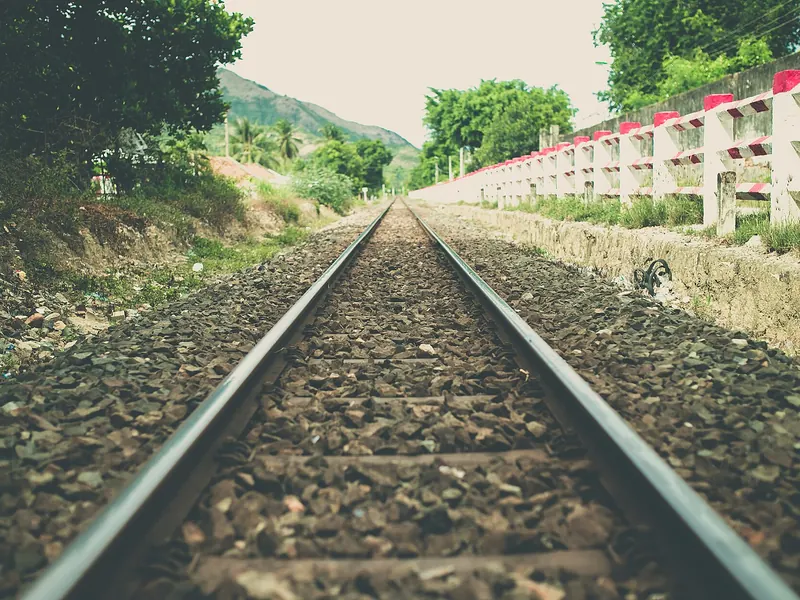 A railway line running straight away into the countryside, the two rails getting closer together in the distance